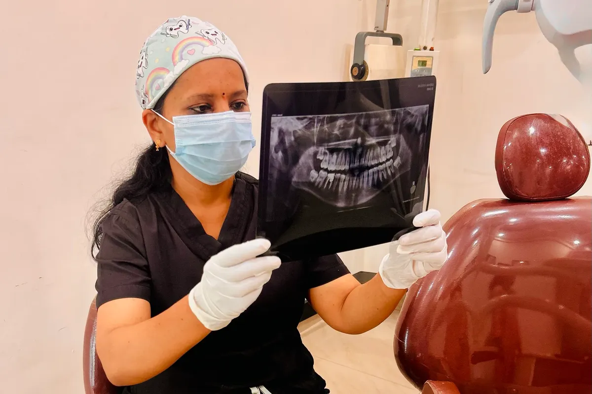 Dentist at Perfect Smile Dental Clinic examining a panoramic dental X-ray beside the treatment chair
